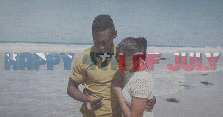 Image of text independence day over african american couple taking photo at beach. patriotism and celebration concept digitally generated image.の写真素材