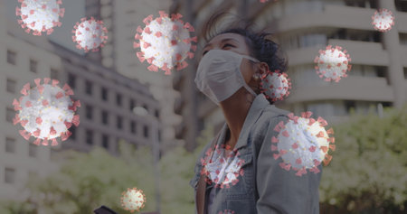Woman wearing mask outdoors surrounded by digital virus graphics, looking upwards. Pandemic,...