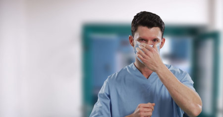 Portrait of male caucasian health worker wearing face mask in hospital. hygiene and infection...