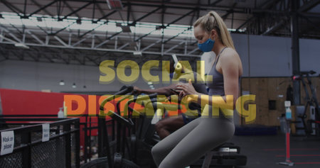 Social distancing text against caucasian woman wearing face mask using smartphone at gym....