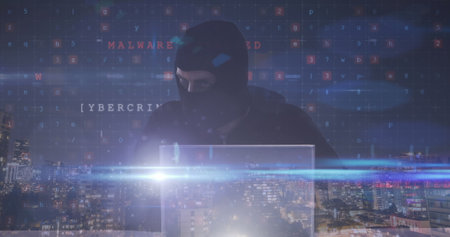 Image of hacker in balaklava using laptop with cyberattack text over cityscape. global online security, cybercrime and digital interface concept digitally generated image.の写真素材