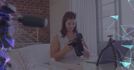 Image of network of connections over female vlogger holding camera recording vlog at home. global...