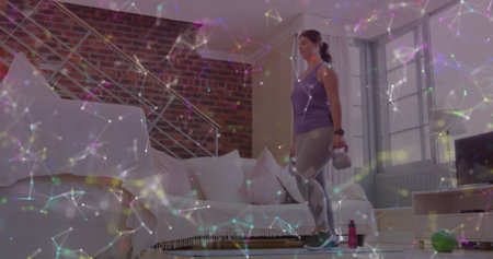 Image of network of connections over woman lifting kettlebells exercising at home. global sports, fitness and active lifestyle concept digitally generated image.の写真素材