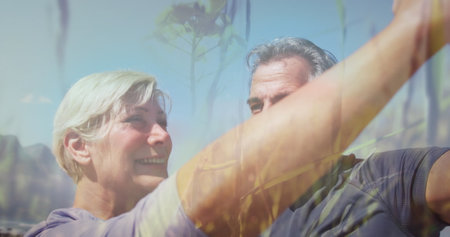 Image of glowing light over smiling senior couple dancing outdoors. retirement and healthy senior...