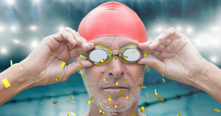 Golden confetti falling over senior male swimmer wearing swimming glasses against swimming pool. sports competition and tournament conceptの写真素材