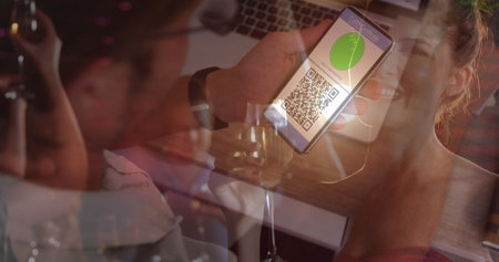 Image of man holding smartphone with covid 19 vaccination passport over people having fun. global covid 19 pandemic and vaccination concept digitally generated image.の写真素材