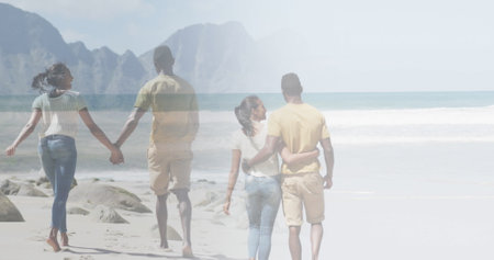 Composite of happy african american couple embracing, and walking holding hands on beach. health, relaxation, romance and wellbeing concept digitally generated image.の写真素材