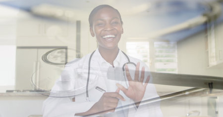 Composite of smiling female doctor talking in image consultation, and stethoscope on desk. medical services, healthcare and technology concept digitally generated image.の写真素材