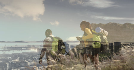 Composite of diverse couple hiking on mountain, and modern cityscape. health, fitness and wellbeing concept digitally generated image.の写真素材