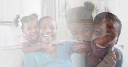 Composite of happy african american mother and daughter embracing and laughing at home. health, family and wellbeing concept digitally generated image.の写真素材