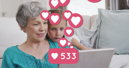 Image of heart icons and number over caucasian grandmother and grandson using tablet. family, love...