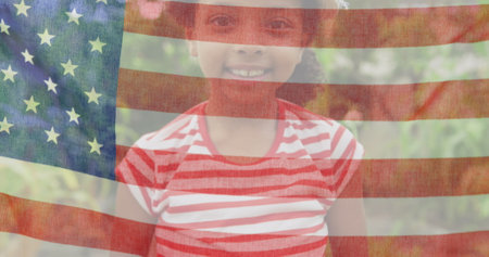 Image of flag of united states of america over smiling african american girl. american patriotism and independence concept digitally generated image.の写真素材