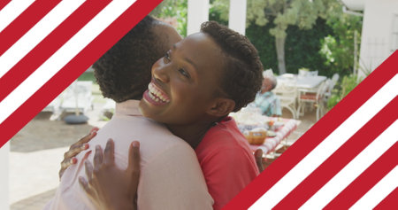 Image of american flag over two smiling women embracing. patriotism and celebration concept digitally generated image.の写真素材