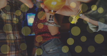 Image of glowing yellow lights over friends having fun making toast. party and celebration concept digitally generated image.の写真素材