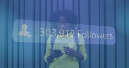 Image of social network notification over african american using smartphone in street. global communication technology and social network concept digitally generated image.の写真素材