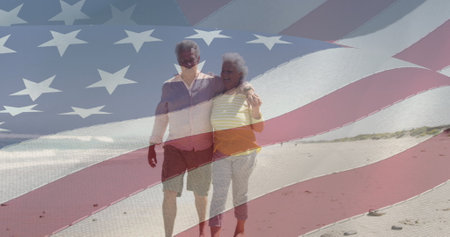 Image of happy senior caucasian couple embracing on beach over flag of united states of america....