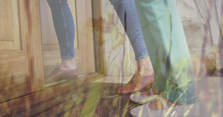 Image of grass moving over midsection of caucasian woman and her daughter opening door. family time at home digitally generated image.の写真素材