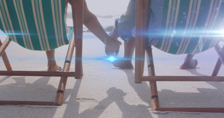 Image of light moving over senior couple on beach deckchairs holding hands. retirement, domestic...