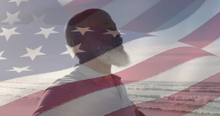 Image of flag of united states of america over senior african american man on beach. american...