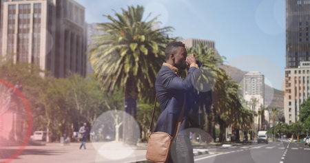 Image of coloured lights over african american man drinking coffee walking to work in street. walk...