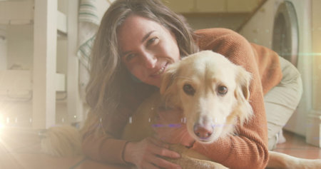 Spot of light against caucasian woman playing with her dog at home. national pet month awareness conceptの写真素材
