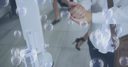 Image of bubbles over caucasian woman disinfecting hands. social media and communication interface...