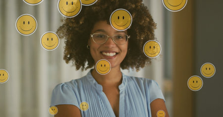 Image of emoji icons over happy biracial woman. social media and communication interface concept digitally generated image.の写真素材