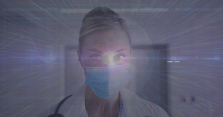 Image of data processing over caucasian female doctor with face mask. global medicine and data processing during covid 19 pandemic concept digitally generated image.の写真素材