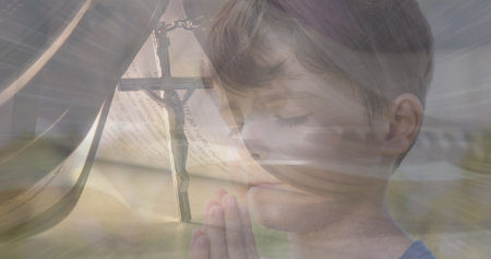 Image of light spots over caucasian boy praying and cross. easter, religion and celebration concept digitally generated image.の写真素材