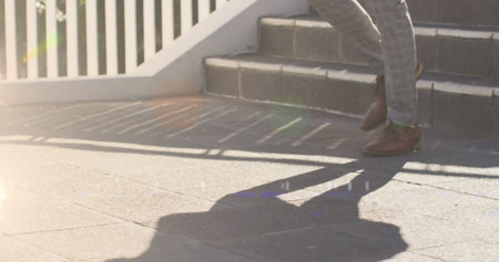 Image of glowing lights over low section of businessman walking down steps. walk to work day concept...