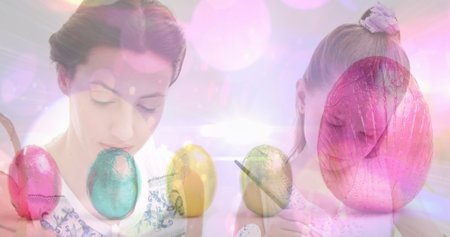 Image of easter eggs over caucasian mother and daughter decorating eggs. easter tradition and celebration concept digitally generated image.の写真素材