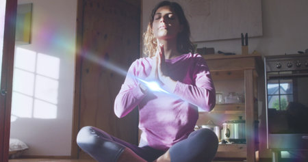 Image of light spots over caucasian woman practicing yoga and meditating. world meditation day and...