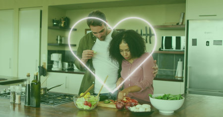 Image of heart icon over happy diverse couple cooking. national vegetarian week and celebration concept digitally generated image.の写真素材