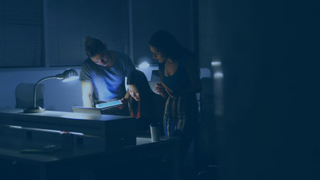 Team is collaborating on laptop, tablet, coffee mug with lamps in flat design office copy space....