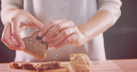 Image of hearts over hands of caucasian woman holding cookies. baking, desserts and celebration...