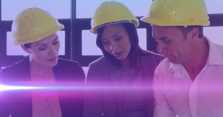 Image of light trails over diverse male and female engineers in office. international women engineering day and celebration concept digitally generated image.の写真素材