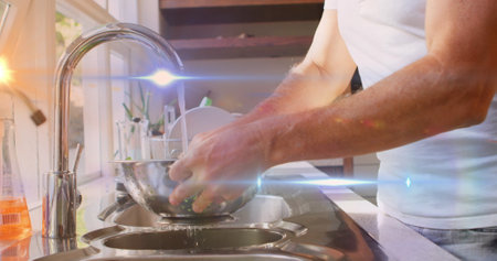 Image of light spots and trails over caucasian man washing vegetables in kitchen. social media and communication interface concept digitally generated image.の写真素材