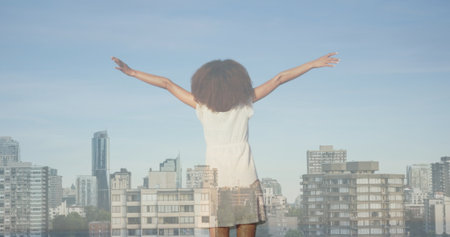 Image of cityscape over african american woman with arms outstretched. never give up day and celebration concept digitally generated image.の写真素材