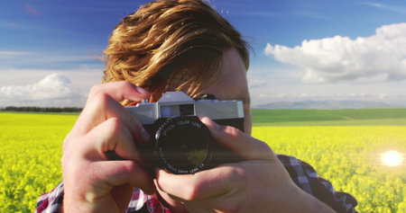 Spot of light against caucasian male photographer clicking pictures with digital camera outdoors....