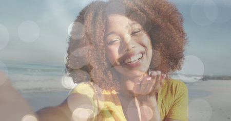 Image of bokeh over happy biracial woman sending kisses. love, romantic relationship and valentines day concept digitally generated image.の写真素材