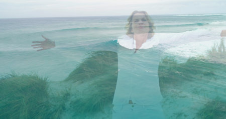 Image of landscape with ocean over caucasian woman at beach. ocean day and celebration concept digitally generated image.の写真素材