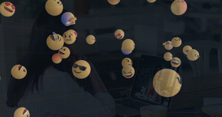 Image of falling emojis over women using laptop. social media and communication concept digitally generated image.の写真素材