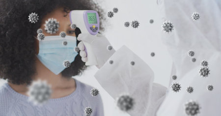 Medic measuring masked woman temperature with infrared thermometer in clinic, with virus graphics. Medical, hygiene, diagnostic, safety, clinical, prevention, healthの写真素材
