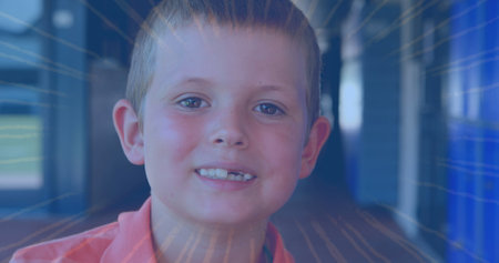 Smiling schoolboy posing with light streaks in school hallway, with blue lockers. Portrait, childhood, education, vibrant, optimistic, energetic, innocenceの写真素材