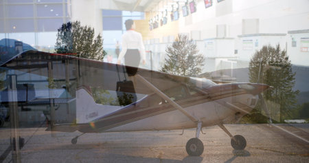 Showing woman in business attire walking through airport check-in with propeller plane and suitcase....