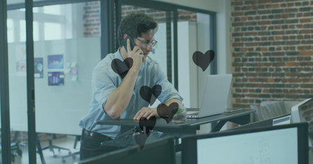 Image of hearts floating over caucasian businessman having call in office. Business and working with...