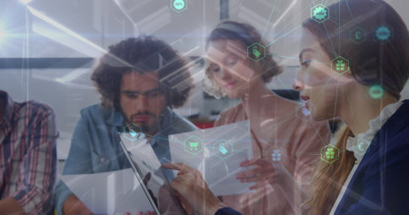 Image of network of connections with icons over diverse female and male coworkers in office....