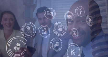 Multiple digital icons over diverse businesspeople exchanging cards and discussing at office....