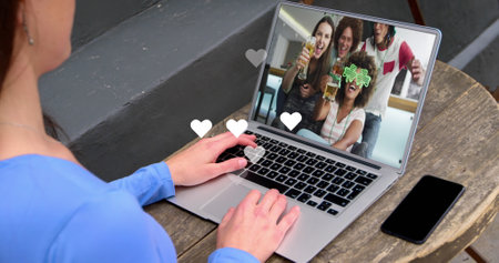 White hearts floating over caucasian woman having a imagecall on laptop at a cafe. Social media networking and business technology conceptの写真素材