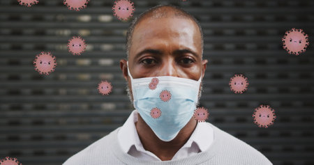 Image of falling covid 19 cells over african american men wearing face mask. Global covid 19 pandemic, science and connections concept digitally generatedの写真素材